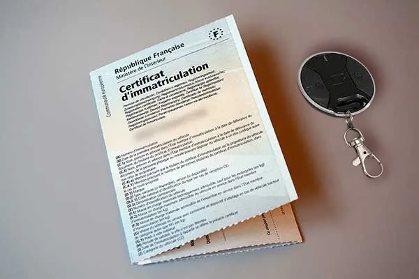 Certificat d'immatriculation français et porte-clés posés sur un bureau