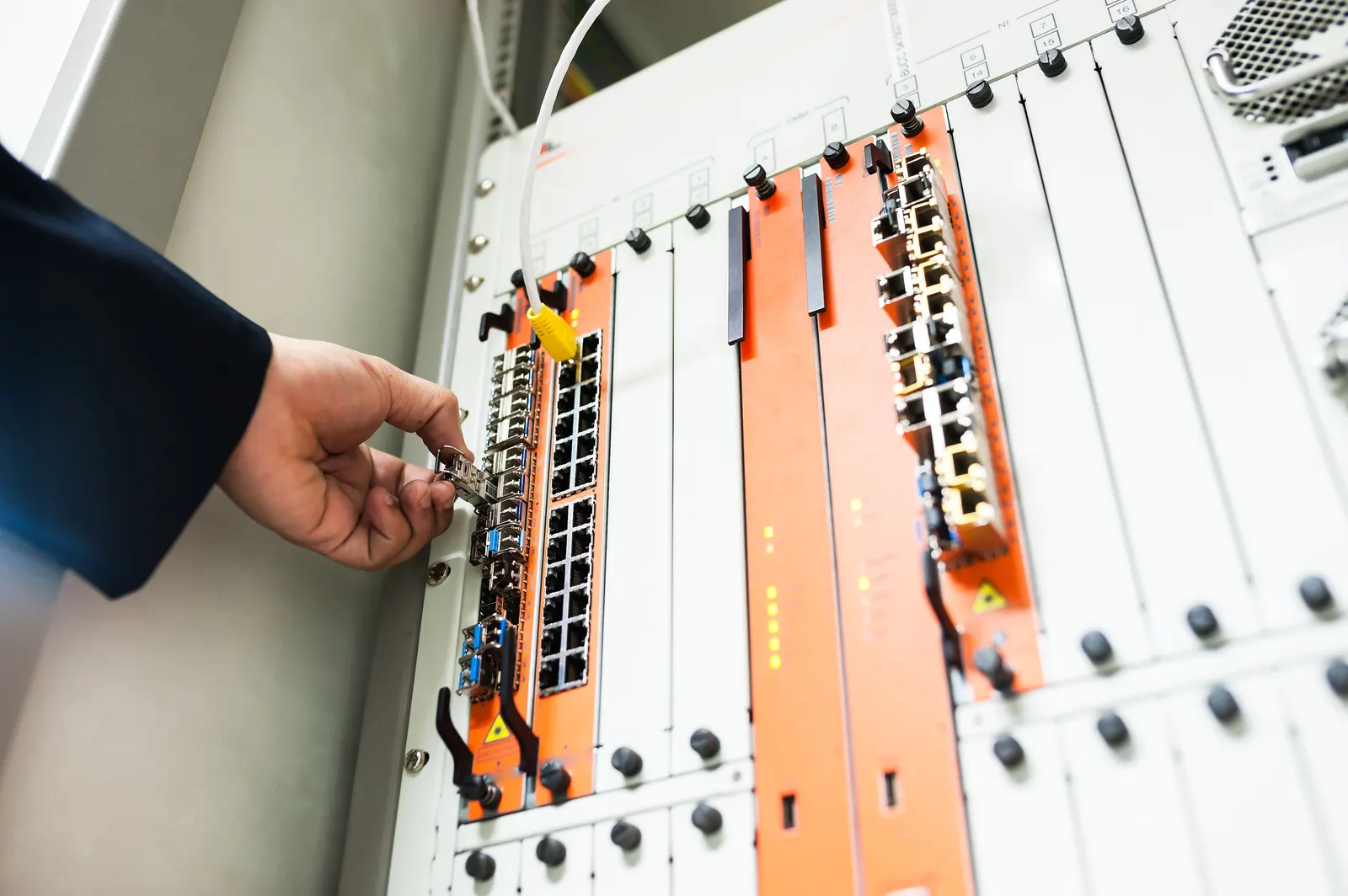 Technicien branchant un module fibre optique dans une baie de brassage