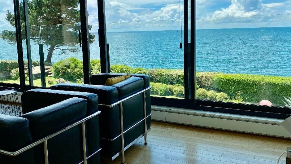 Salon vitré avec vue mer depuis une maison en bord de mer en Bretagne