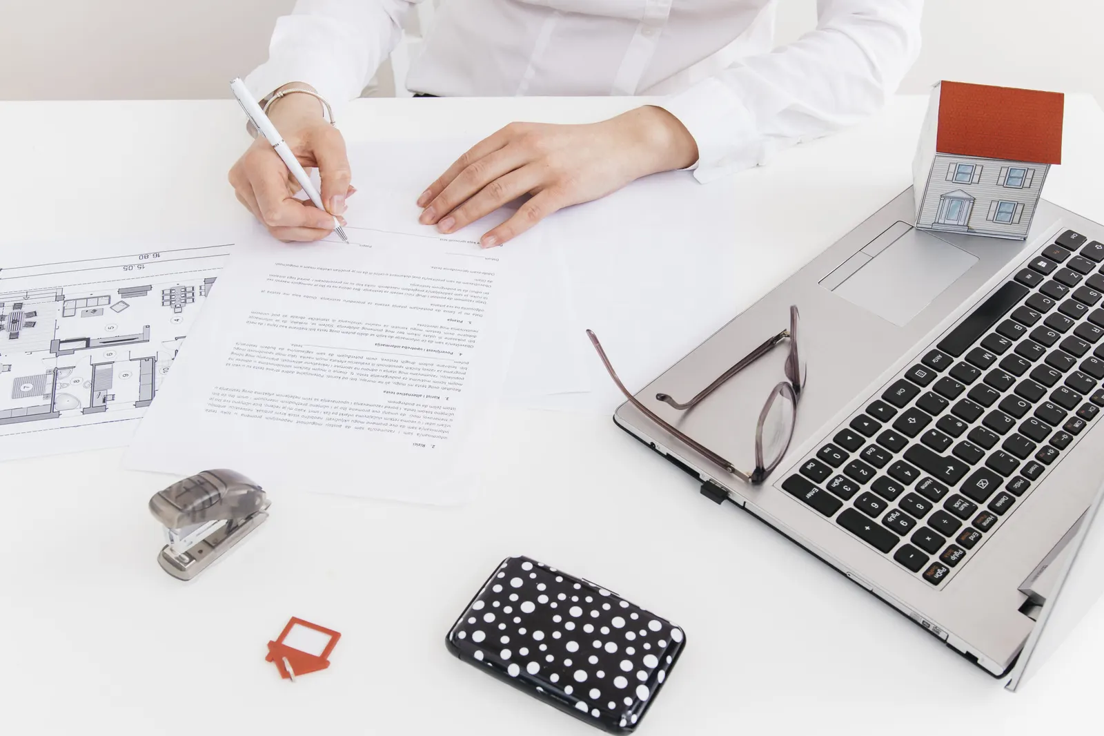 Signature d'un dossier de vente immobilière avec plan de maison