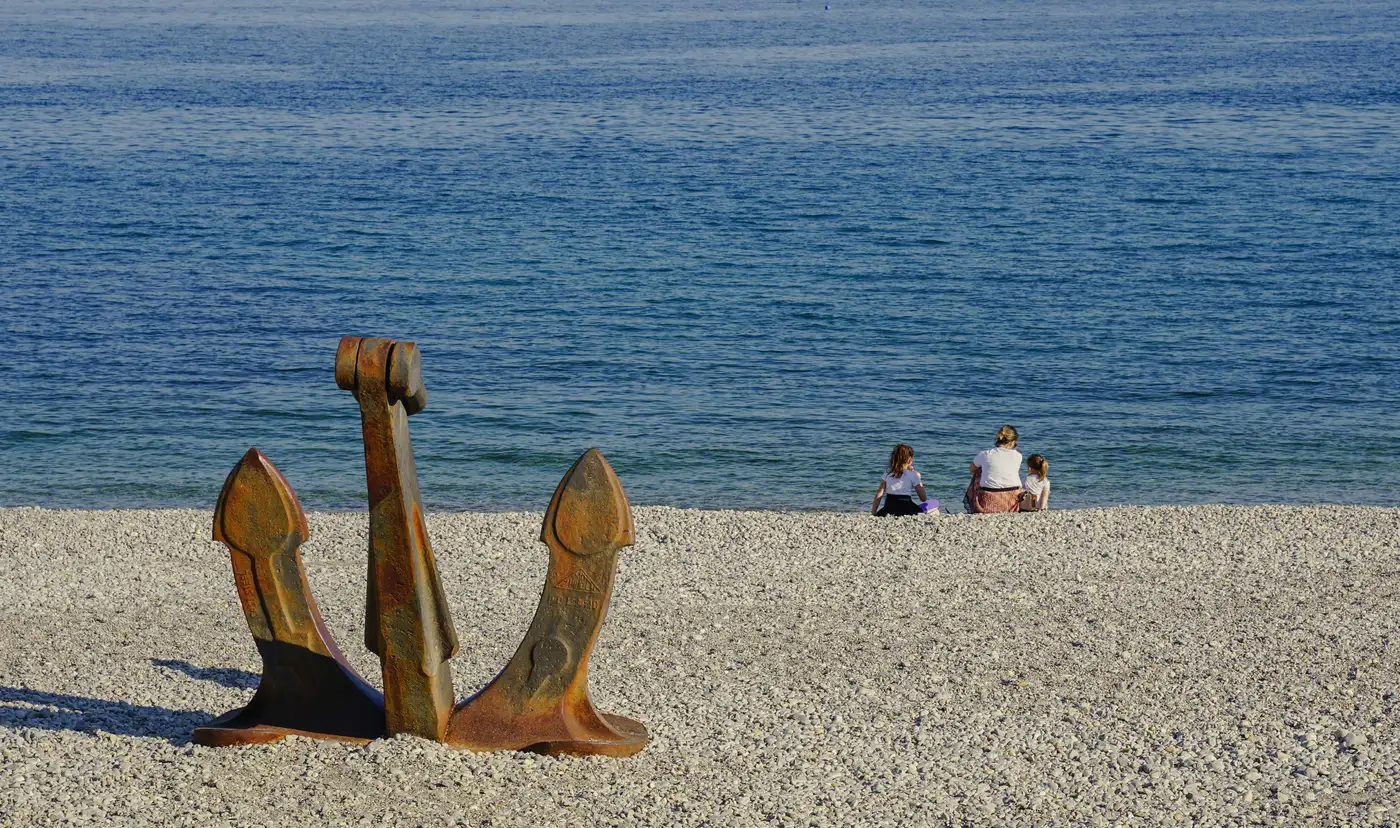 Ancre bretonne sur une plage de galets avec une famille face à l'océan